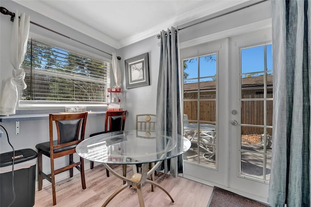 dining space featuring ornamental molding, wood finished floors, and a healthy amount of sunlight
