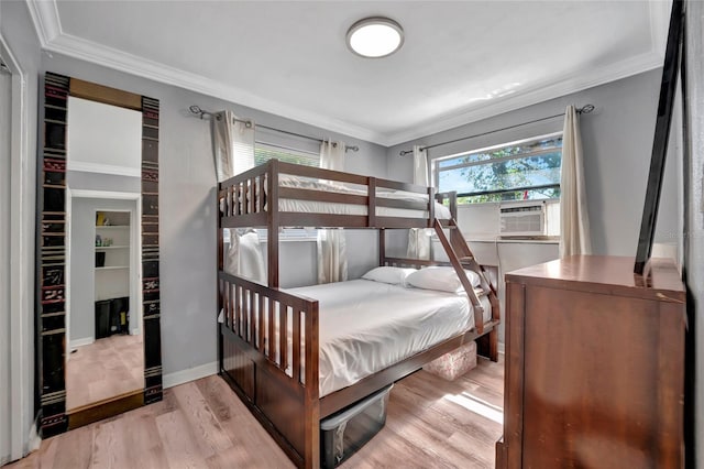 bedroom with ornamental molding, cooling unit, and light wood finished floors