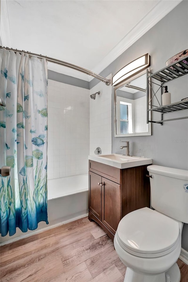bathroom featuring toilet, ornamental molding, wood finished floors, shower / bath combo with shower curtain, and vanity