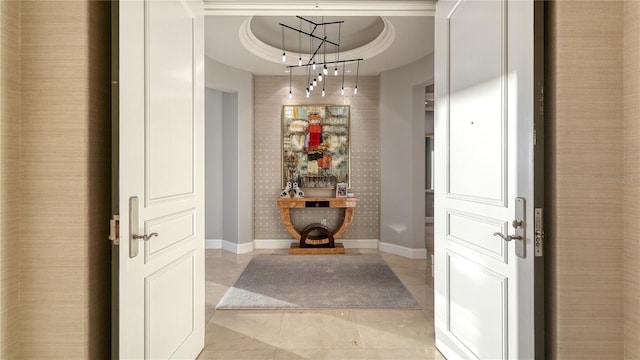 hall featuring light tile patterned flooring, baseboards, and a tray ceiling