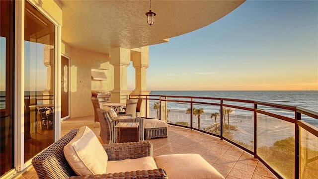 balcony at dusk featuring a water view