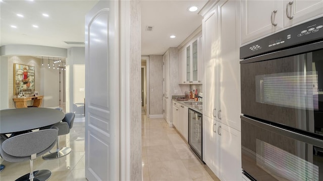 kitchen with glass insert cabinets, recessed lighting, white cabinets, dobule oven black, and a sink