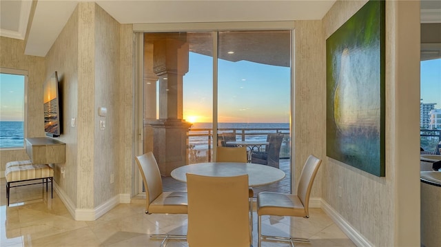 dining room with wallpapered walls, baseboards, and a water view