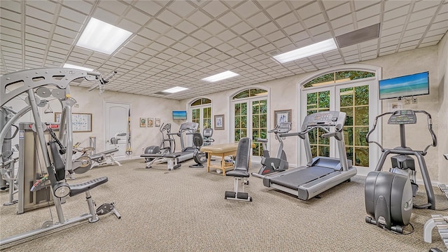 gym with french doors, a paneled ceiling, and carpet