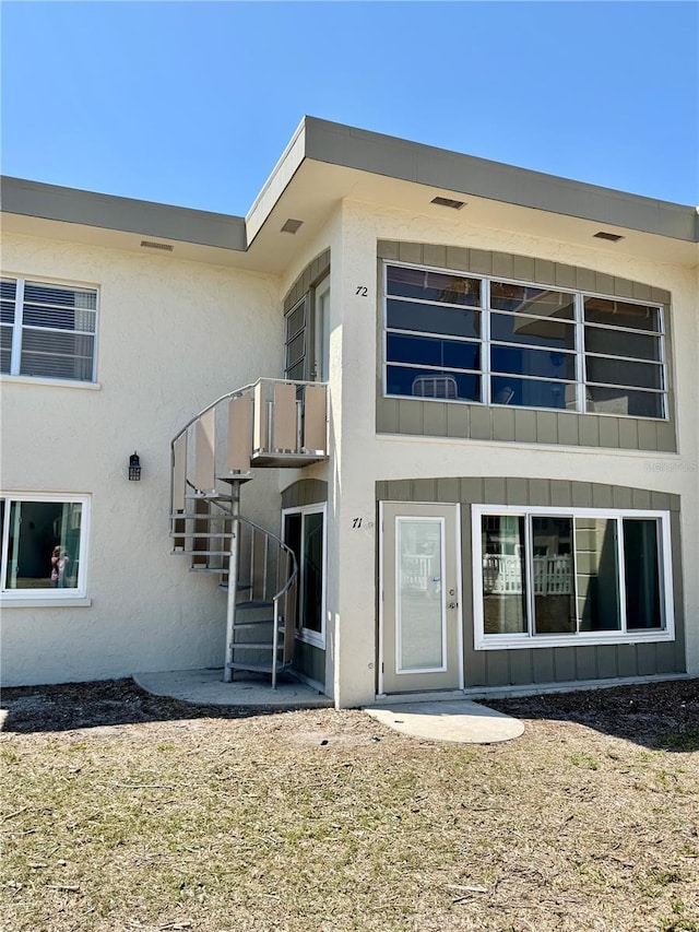 back of property featuring stucco siding and stairs