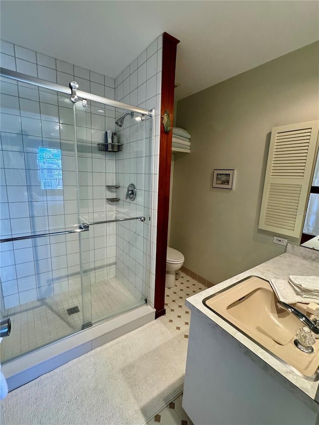 full bath featuring vanity, a shower stall, toilet, and baseboards