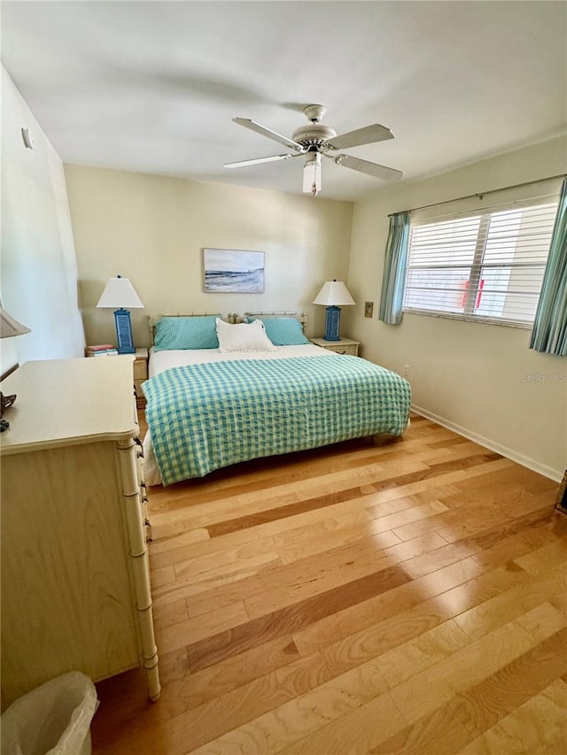 bedroom with ceiling fan, baseboards, and light wood-style flooring