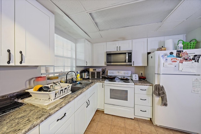 kitchen with a sink, a drop ceiling, white appliances, and white cabinets