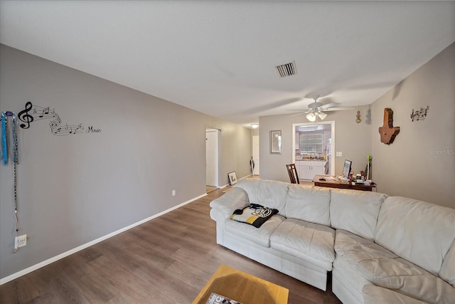 living area with visible vents, a ceiling fan, baseboards, and wood finished floors