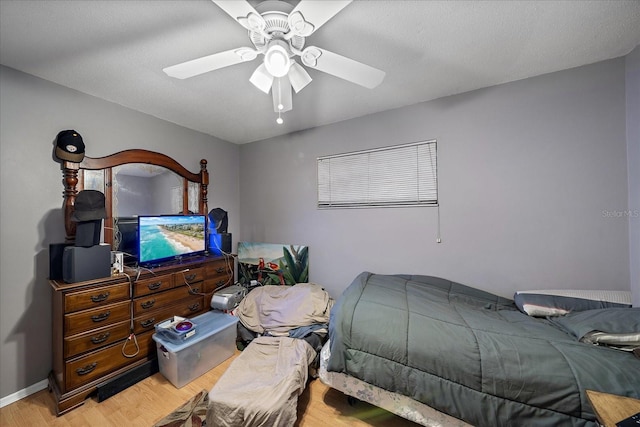 bedroom featuring baseboards, wood finished floors, and a ceiling fan