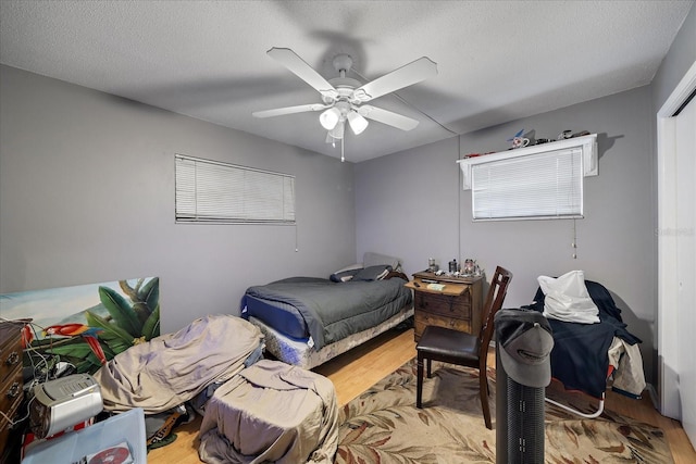 bedroom with a textured ceiling, ceiling fan, and wood finished floors