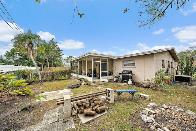 back of house with stucco siding, fence, and a sunroom