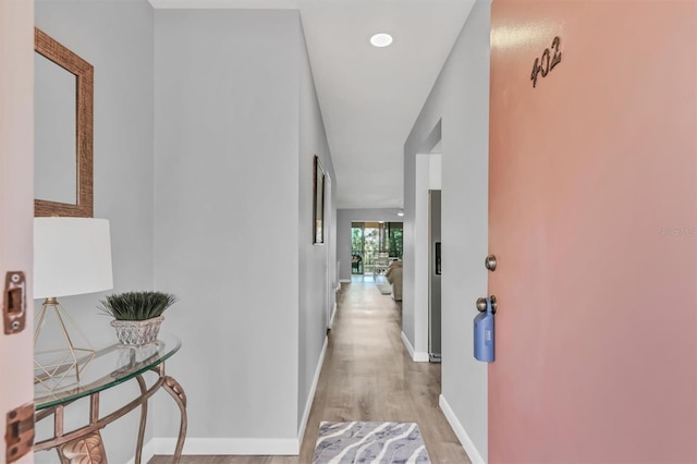 hallway with light wood-type flooring and baseboards