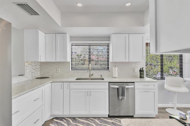 kitchen with visible vents, backsplash, stainless steel dishwasher, white cabinets, and a sink