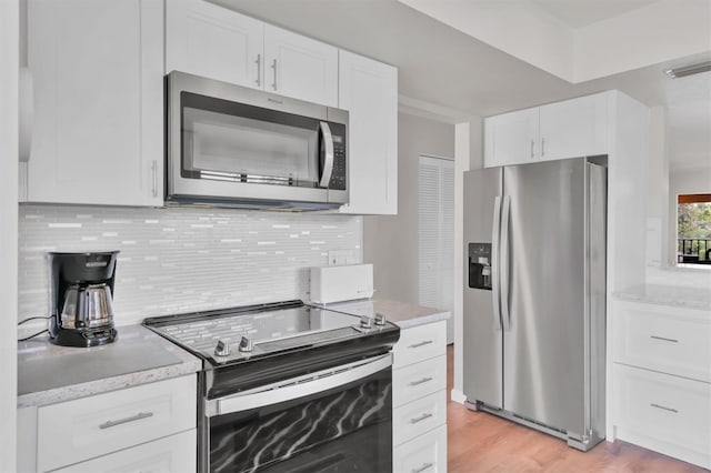 kitchen with visible vents, light wood-style flooring, backsplash, appliances with stainless steel finishes, and white cabinets