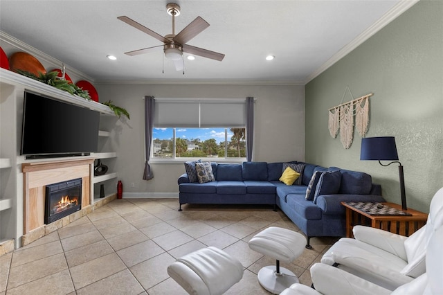 living area featuring ornamental molding, a glass covered fireplace, tile patterned flooring, and a ceiling fan