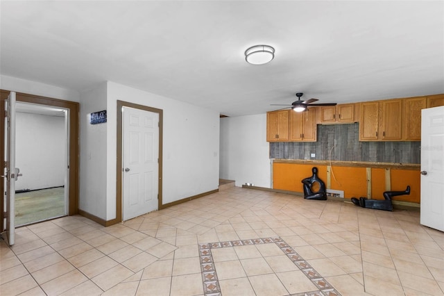 kitchen with light tile patterned floors, ceiling fan, baseboards, backsplash, and brown cabinets