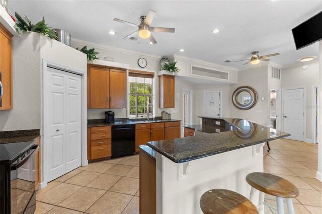 kitchen with brown cabinetry, a kitchen breakfast bar, black appliances, and light tile patterned floors