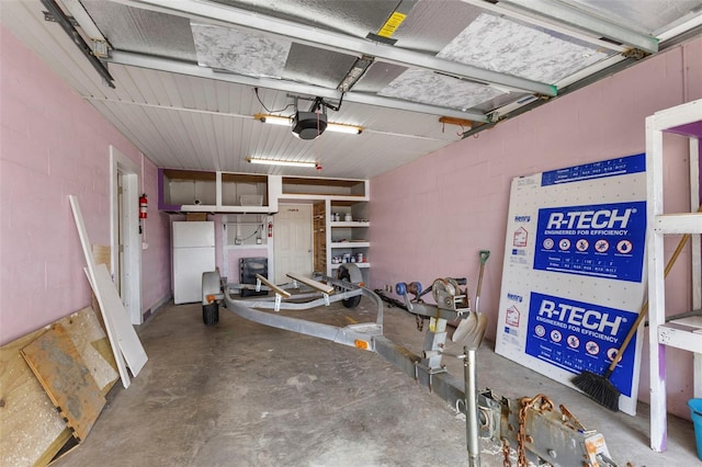 garage with a garage door opener, freestanding refrigerator, and concrete block wall