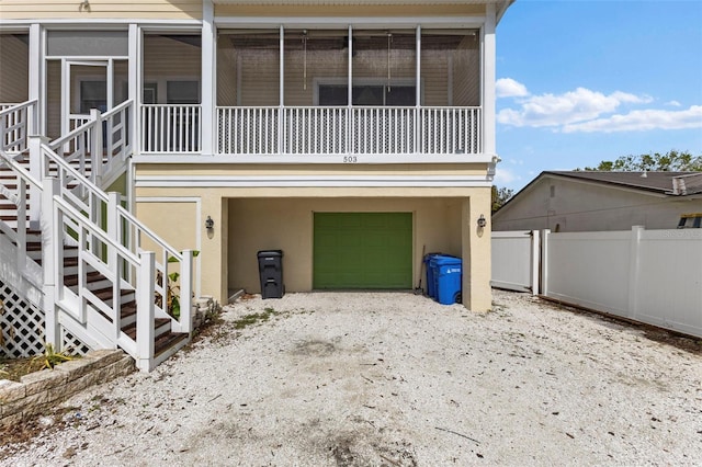 exterior space featuring a sunroom, stucco siding, fence, and stairs