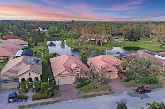 aerial view at dusk with a water view and a residential view