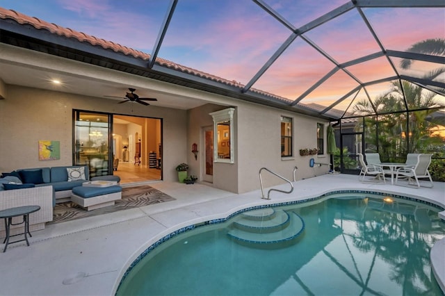 pool at dusk featuring glass enclosure, a patio area, ceiling fan, an outdoor pool, and an outdoor living space