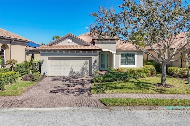 mediterranean / spanish-style house featuring a front yard, decorative driveway, an attached garage, and stucco siding