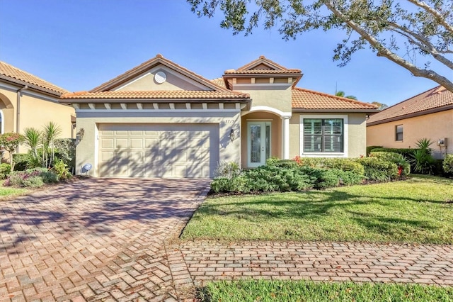 mediterranean / spanish-style house with an attached garage, a tiled roof, decorative driveway, stucco siding, and a front yard