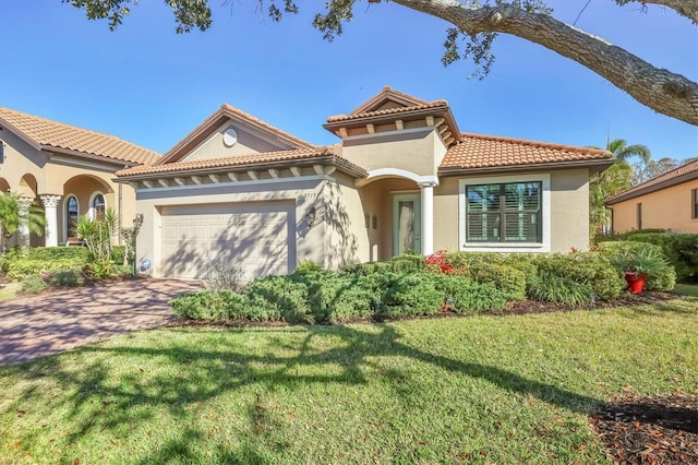 mediterranean / spanish house with a garage, a tile roof, driveway, stucco siding, and a front yard