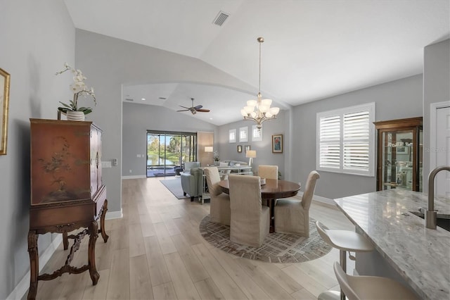 dining space with arched walkways, visible vents, baseboards, vaulted ceiling, and light wood-type flooring