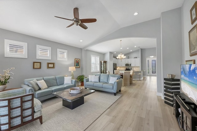 living room featuring arched walkways, lofted ceiling, ceiling fan with notable chandelier, light wood-style floors, and recessed lighting