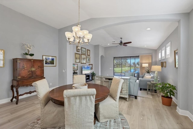 dining space with arched walkways, light wood finished floors, vaulted ceiling, and baseboards