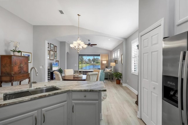 kitchen with lofted ceiling, a sink, visible vents, open floor plan, and stainless steel fridge