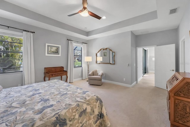 bedroom featuring light carpet, a raised ceiling, visible vents, and baseboards