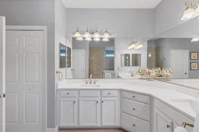 bathroom with a closet, tiled shower, a sink, and double vanity