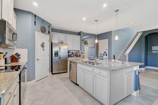 kitchen with white cabinets, arched walkways, stainless steel appliances, and a sink