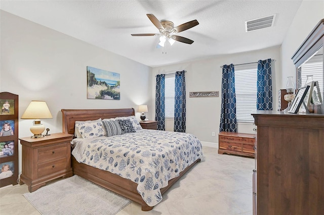 bedroom with visible vents, a ceiling fan, light tile patterned flooring, a textured ceiling, and baseboards