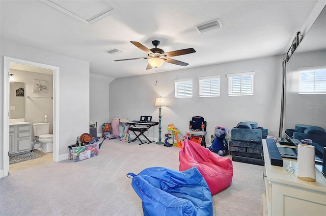 recreation room with carpet, a textured ceiling, visible vents, and a ceiling fan