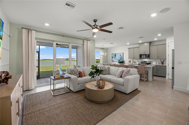 living area with ceiling fan with notable chandelier, visible vents, and recessed lighting