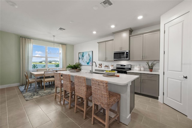 kitchen with appliances with stainless steel finishes, visible vents, a sink, and gray cabinetry