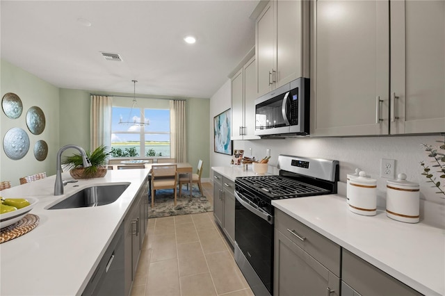 kitchen with visible vents, gray cabinets, stainless steel appliances, light countertops, and a sink