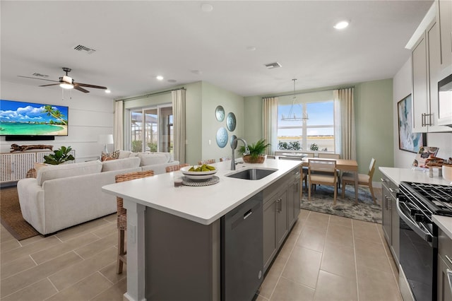 kitchen featuring dishwasher, light countertops, a sink, and range with gas stovetop