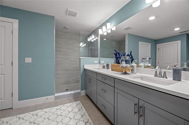 bathroom featuring visible vents, a walk in shower, a sink, and tile patterned floors