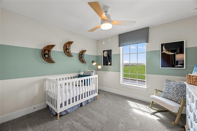 carpeted bedroom featuring ceiling fan, a crib, and baseboards