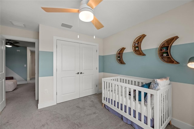 carpeted bedroom with a closet, visible vents, a ceiling fan, a nursery area, and baseboards