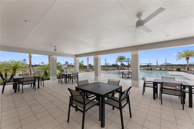 view of patio / terrace with ceiling fan, a community pool, fence, and outdoor dining area