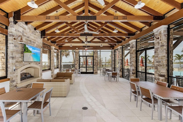 interior space featuring an outdoor living space with a fireplace, outdoor dining area, a ceiling fan, and a gazebo