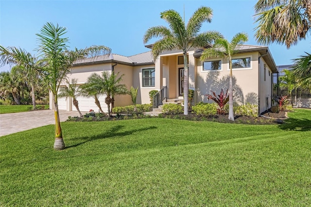 view of front of home featuring decorative driveway, stucco siding, metal roof, a garage, and a front lawn