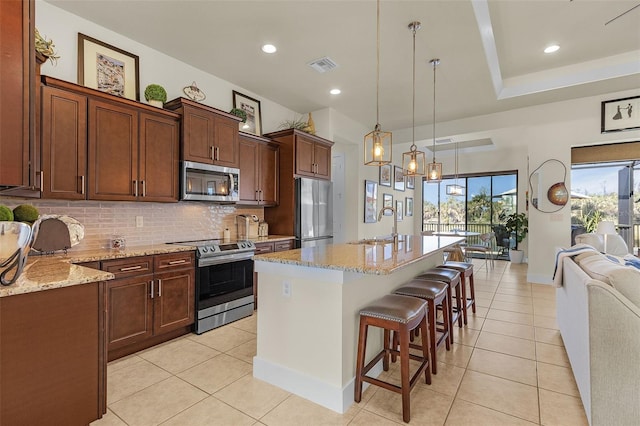 kitchen featuring visible vents, appliances with stainless steel finishes, a kitchen breakfast bar, a sink, and backsplash