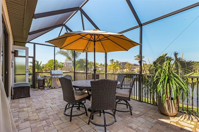 view of patio with glass enclosure, a grill, and outdoor dining space